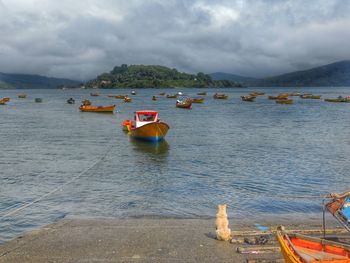 Boats in sea against cloudy sky