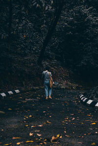 Rear view of woman walking on road in forest