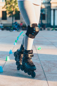 Low section of woman inline skating on footpath