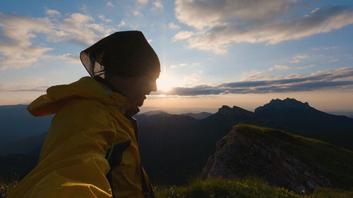 Rear view of woman standing on mountain against sky