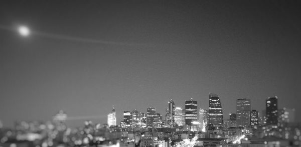 Illuminated cityscape against clear sky at night