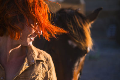 Smiling woman standing by horse