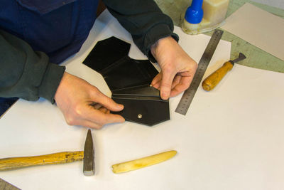 Midsection of man making wallet on table