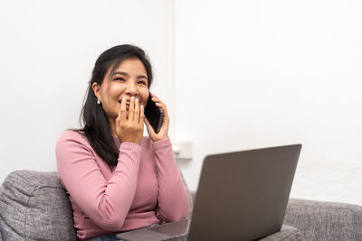 Young woman using laptop while sitting on table