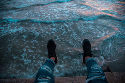 Low section of man sitting by sea