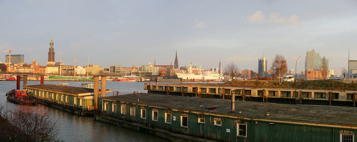 Bridge over river by buildings in city against sky