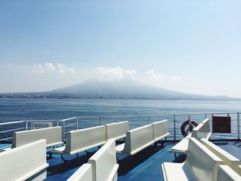 Empty seats of ferry boat at sea against sky