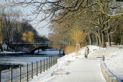 Rear view of woman walking on snow covered walkway during winter