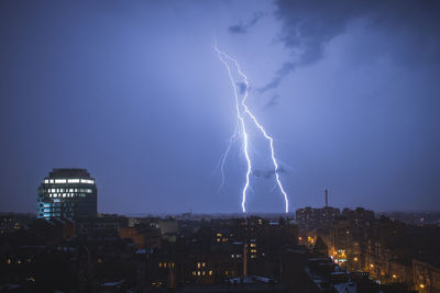 Lightning over illuminated buildings in city at night