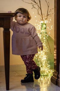 Girl looking at illuminated christmas tree on floor at home