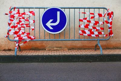 Arrow symbol on barricade on footpath against wall