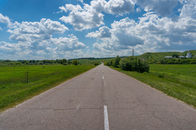 Road amidst field against sky