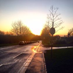 Cars on road against sky at sunset