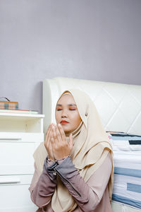 Young woman standing against white wall