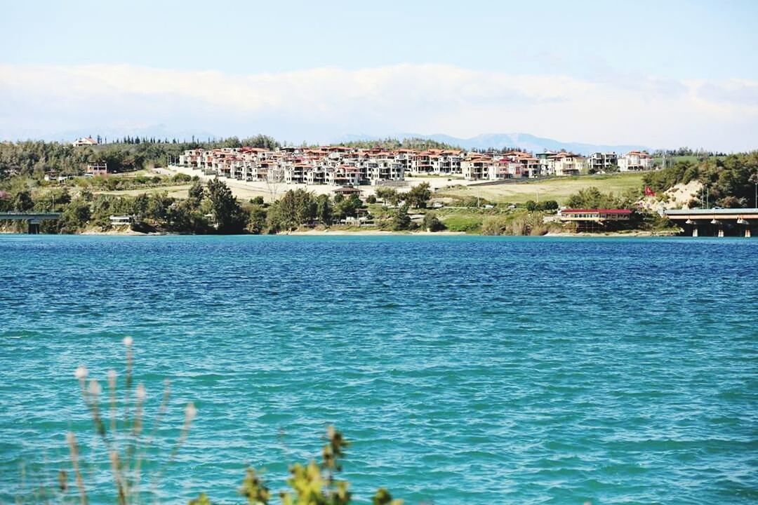 architecture, building exterior, water, built structure, waterfront, sky, blue, tree, river, residential structure, sea, house, rippled, city, residential building, day, town, travel destinations, cloud, outdoors