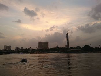 City at waterfront against cloudy sky