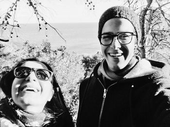 Portrait of happy man with mother in forest against clear sky