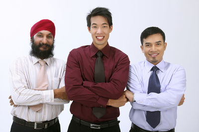 Portrait of smiling businessmen standing against white background