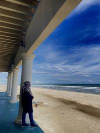 Rear view of people walking at beach against sky