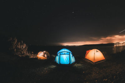 Illuminated tent on field against sky at night