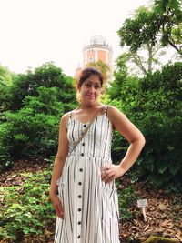 Portrait of a smiling young woman standing against trees