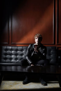 Full length of man sitting on sofa at home