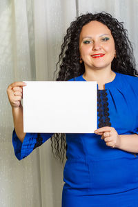 Portrait of smiling woman standing against wall