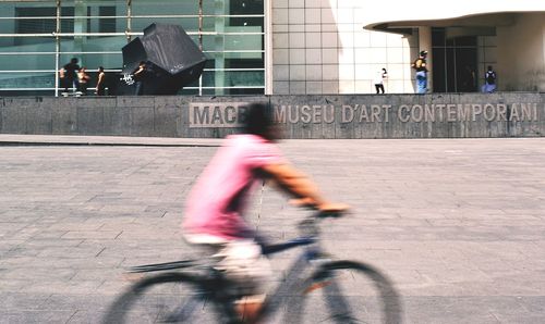 Rear view of woman riding bicycle on street
