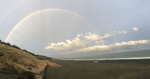 Scenic view of sea against rainbow in sky