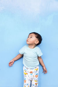 Cute girl standing against blue wall