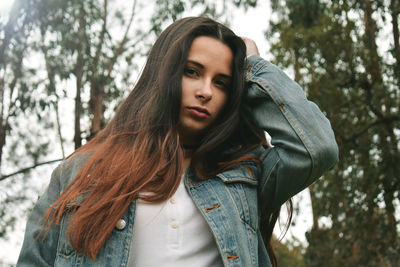 Portrait of beautiful young woman wearing denim jacket in park