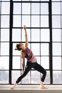Female athlete practicing yoga by window in gym