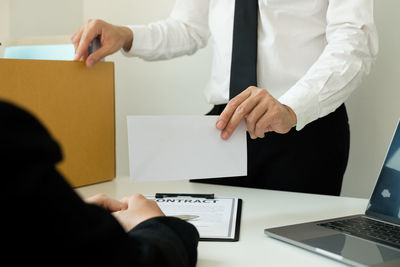 Midsection of man using mobile phone while sitting on table