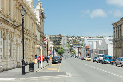 Cars on street in city against sky