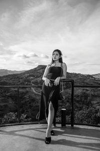 Full length portrait of woman standing on mountain against sky