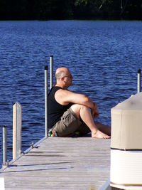 Man sitting on jetty over sea