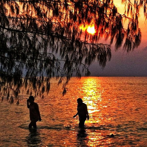 SILHOUETTE PEOPLE ON SEA AGAINST SKY DURING SUNSET