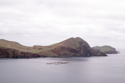 Scenic view of sea by mountain against sky