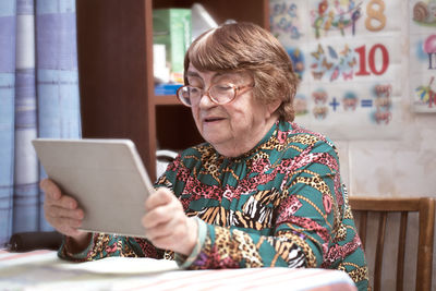 Senior woman using digital tablet while sitting on table