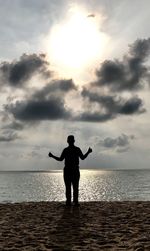 Rear view of silhouette man standing on beach against sky