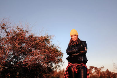 Portrait of happy young woman standing against clear sky