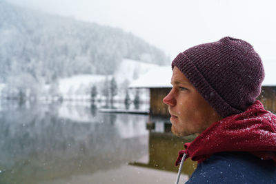 Close-up of man in warm clothing at lake against sky