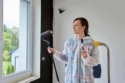 Side view of young woman looking through window