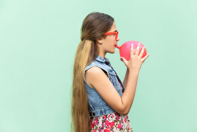 Side view of woman drinking glass against white background