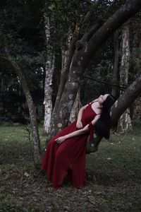 Side view of young woman relaxing on tree trunk in forest