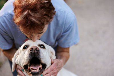 Woman kissing dog on top of head