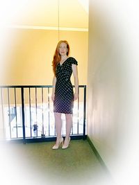 Full length portrait of young woman standing against wall