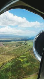 Close-up of airplane wing over landscape against sky