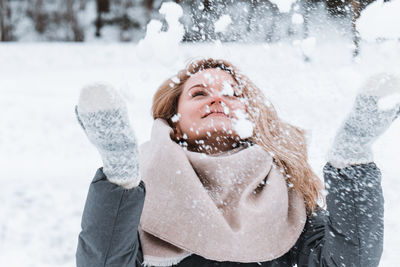 Portrait of smiling young woman drinking water on snow