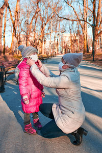 Woman wearing mask to girl standing on road